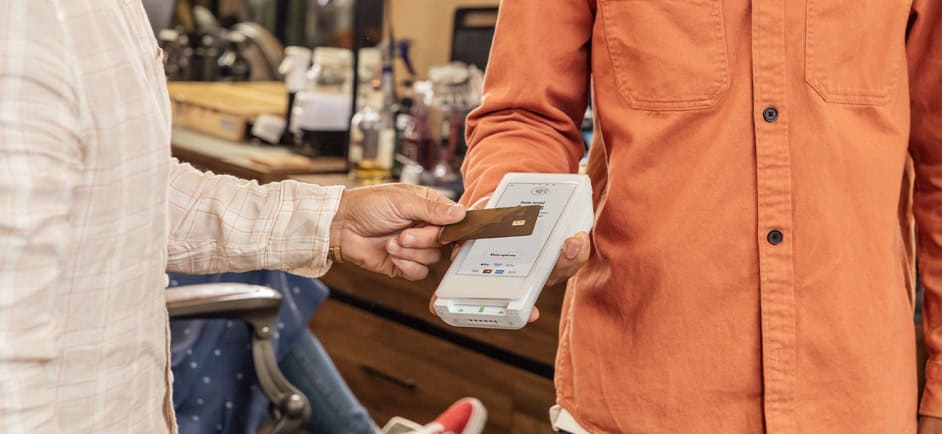 A man is tapping his credit card on a card scanner in a store.